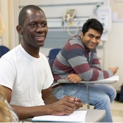 Two young men of different diversities sitting in classroom.